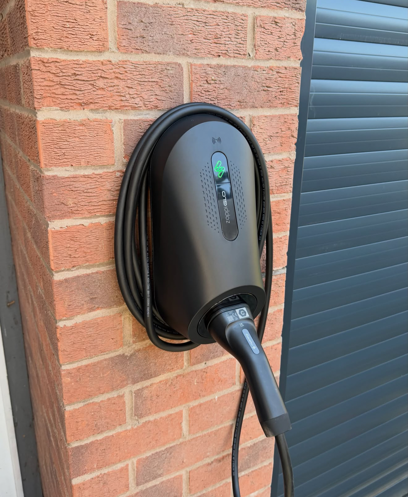 Tethered myenergi zappi home EV charger installed beside a garage door