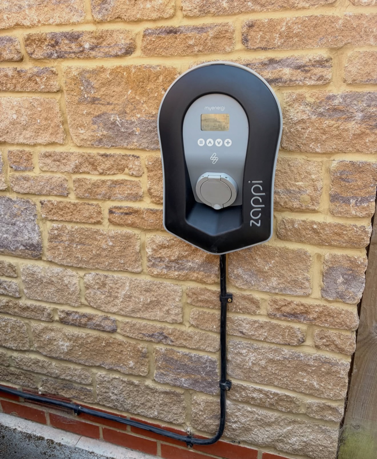 Socketed myenergi zappi EV charger installed on a stone wall